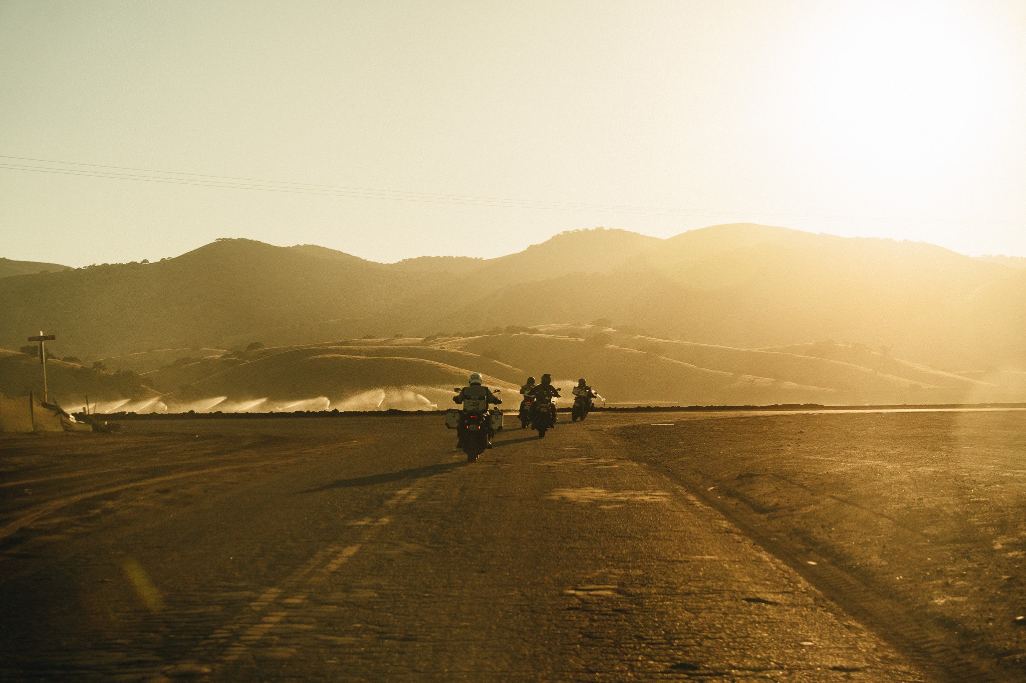 Small group of riders on a golden-hour desert road